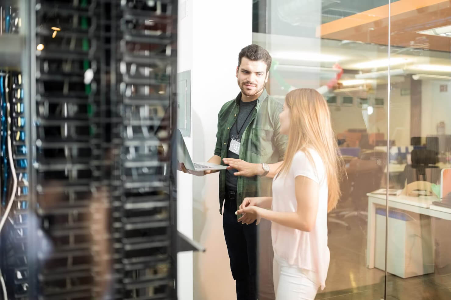 Two business people standing in server room with laptop and discussing site speed