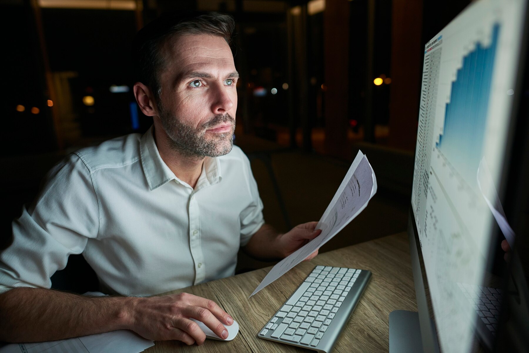 Focused man with document using computer. He is checking A:B testing on content pages for WP site