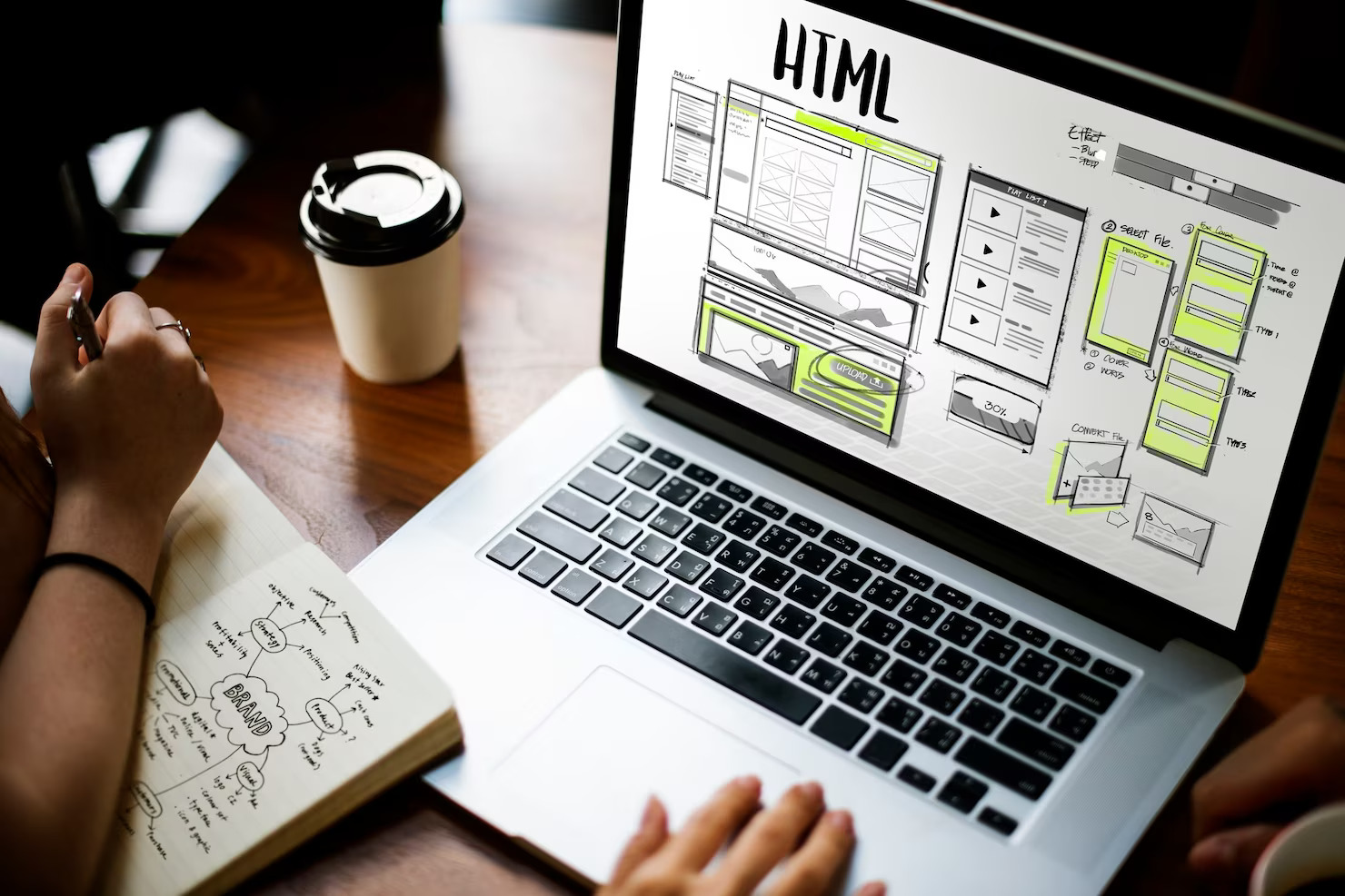 Online web design. Web designer creating visual elements on paper and on a laptop screen