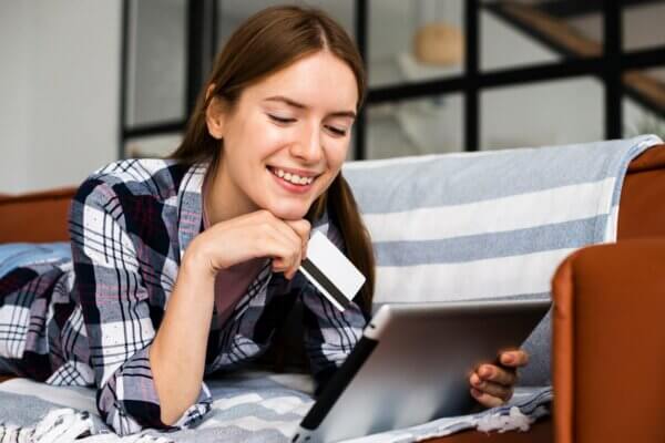 Woman smiling and holding a credit card. She had a positive shopping experience on WooCommerce online shop