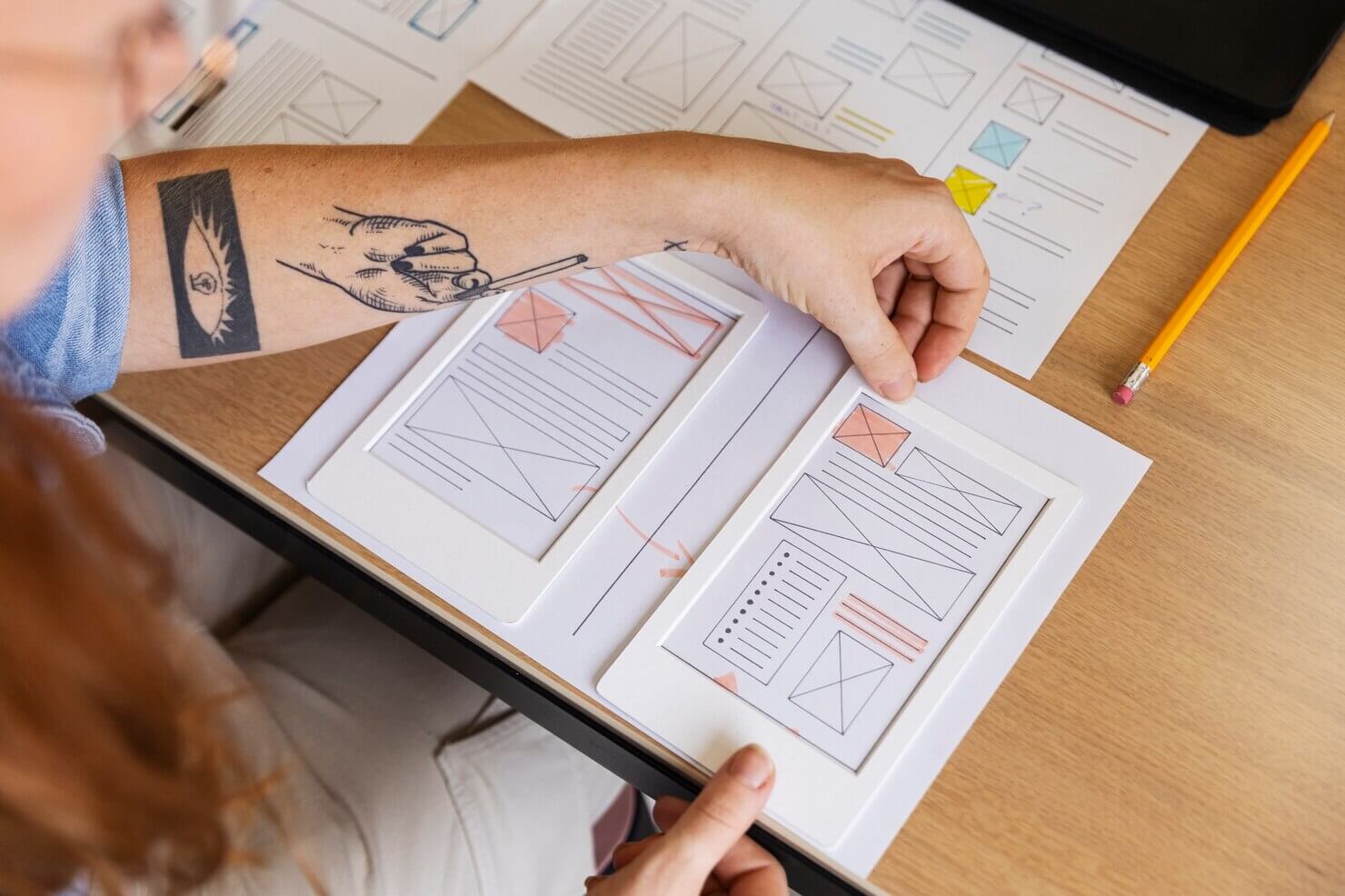 Female web designer taking notes in the office to create a hierarchy of design elements on mobile