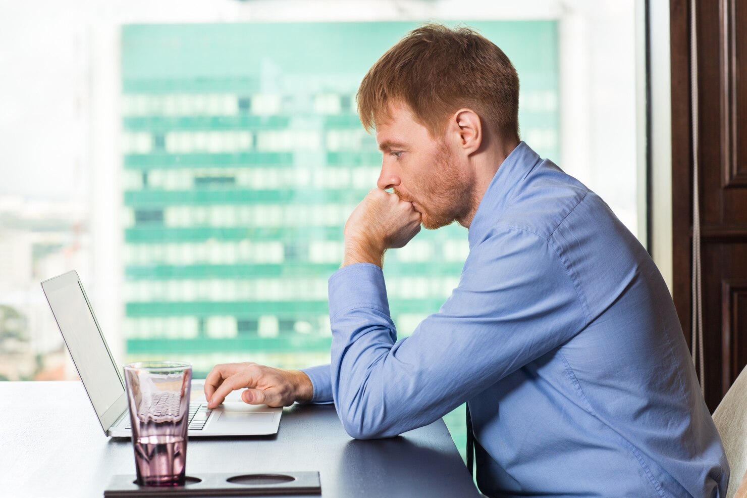 Man biting his nails while looking at a laptop. Man is worried about his slow loading wordpress website, due to the use of popular builders
