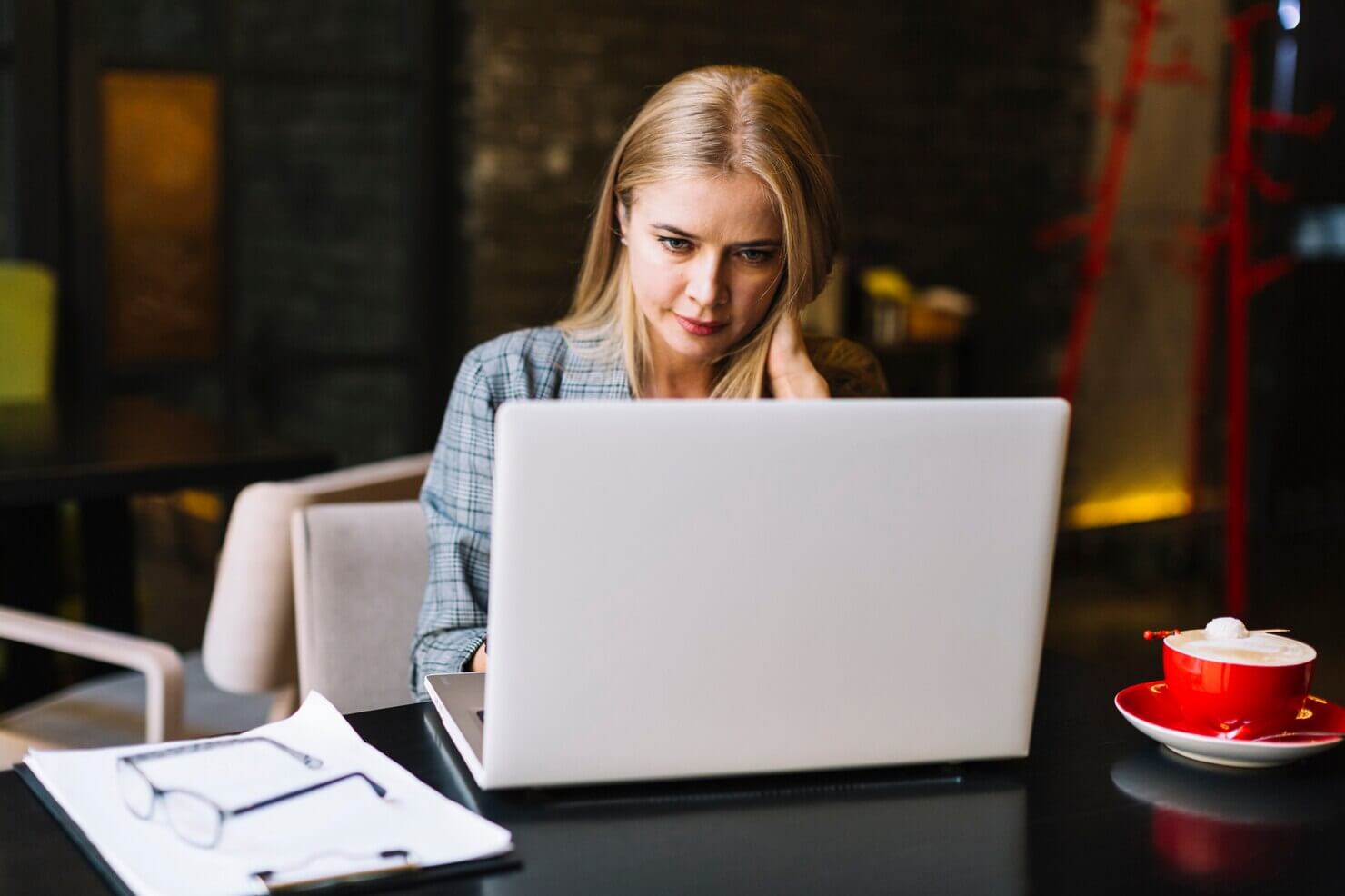 Stylish businesswoman with laptop in cosy coffee shop. She is looking over results after auditing website pop ups and ctas