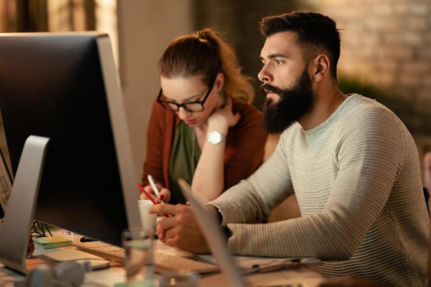 Young entrepreneur using computer while working with his colleagues in the office. Reseaching integration of user behavior insights as part of website audit trends