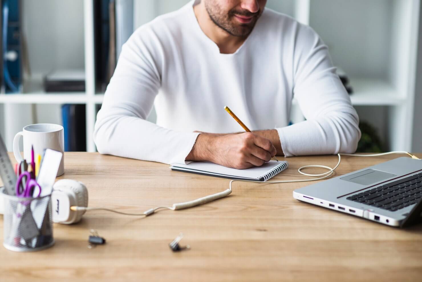 Businessman writing on notepad over wooden desk on crafting long form content in WordPress
