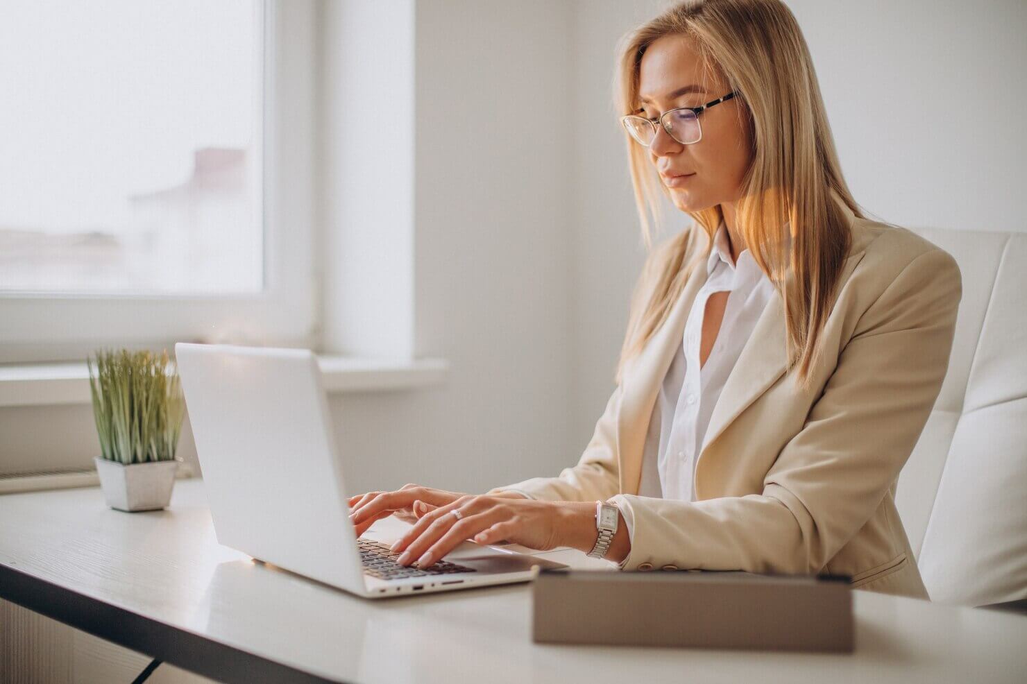 Young business woman working on computer in office typing out the hidden costs of ignoring regular website audits